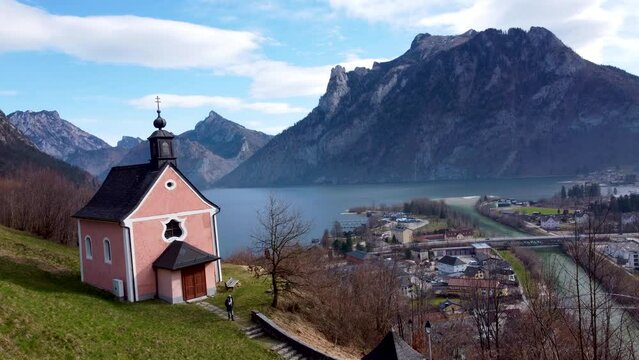 Tourist is walking near chapel on Kalvarienberg overlooking Traunsee in Ebensee, Upper Austria, framed by Alps