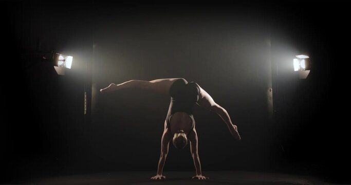 Acrobat does handstand and flexible leg movements during performance on stage