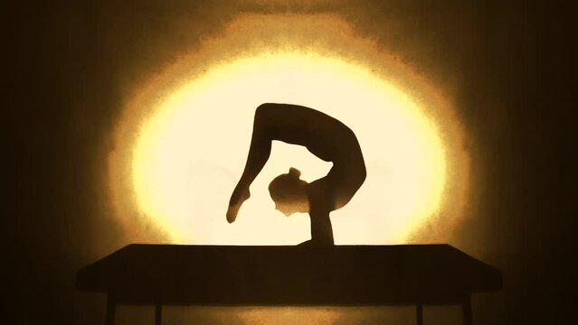 Woman bending doing acrobatics with a yellow light behind. Slow motion.
