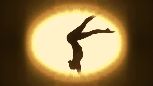 Silhouette of a lithe acrobatic woman making movements in studio