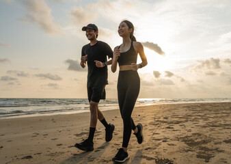 Asian Couple jogging and running outdoors sea sand beach. Sporty people wearing sportswear jogging. Male female athlete running during sunset on the beach. Workout exercise. Healthy and lifestyle.