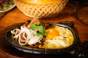 Bo ne trung, beef cooked in a hot plate with gravy, eggs and corn which is a westernized vietnamese breakfast