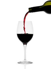 Red wine pouring from a bottle in a glass with splash isolated on white background