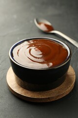 Tasty barbeque sauce in bowl on dark table, closeup