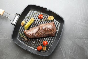 Delicious grilled beef meat and vegetables in pan on grey table, top view