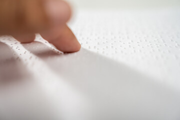 Hand of a blind person reading some braille text on page paper to learn. Finger of blind student...