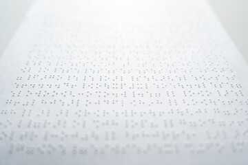 Close up some braille text on page paper written by blind. Blind man using slate and stylus tools making embossed printing the braille alphabet Code on sheet.