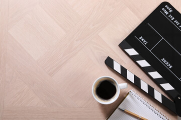 Movie clapper, coffee, notebook and pen on wooden table, flat lay. Space for text