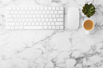 Office workplace. Keyboard, mouse, coffee and houseplant on white marble table, flat lay. Space for...