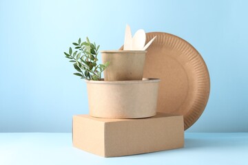 Eco friendly food packaging. Paper containers, tableware and green twig on white table against...