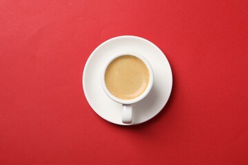 Aromatic coffee in cup on red background, top view