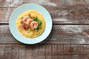 Plate with fresh tasty shrimps, bacon, grits and green onion on wooden table, top view. Space for...