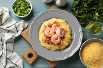 Plate with fresh tasty shrimps, bacon, grits and green onion on light blue wooden table, flat lay
