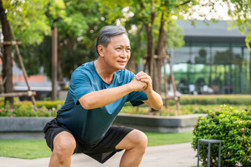 Senior old asian man wearing sportswear warming up before running outdoor. Portraits of Mature man stretching body before running at public park. Training athlete work out at outdoor nature