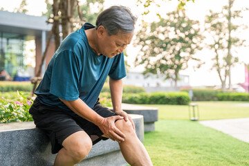 Mature man tired and leg pain during jogging at nature park. Runner has sore knees because he has been running for too long. Exercising until the injury. Training athlete work out at outdoor.