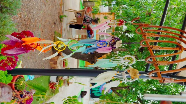 Colorful dream catchers representative of the chakras with feathers hanging in an outdoor tent moving with the wind. Vertical video.