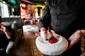 The central focus of the image is a pair of hands delicately holding a white, textured plate. The...
