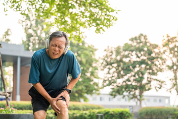 Mature man tired and leg pain during jogging on the at nature park. Runner has sore knees because he has been running for too long. Exercising until the injury. Training athlete work out at outdoor.