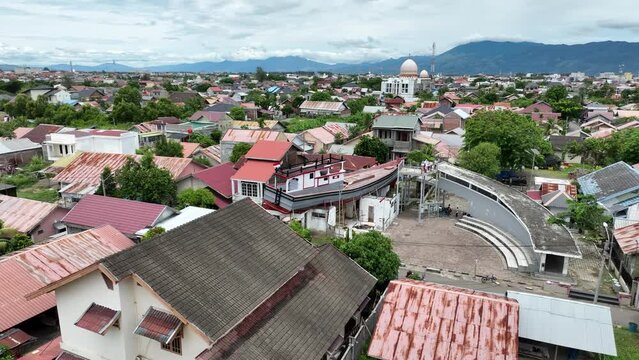 Banda aceh with boats on rooftops, a reminder of the 2004 tsunami, on a cloudy day, aerial view