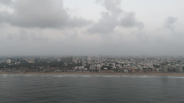 A sweeping drone footage showcasing the urban landscape of Chennai, with clouds casting dramatic shadows over Beach.
