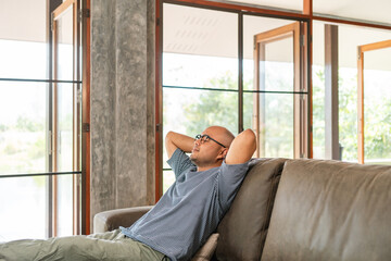 Handsome asian man sitting rest on sofa couch in living room at home. Happy Portrait of cheerful smiling asian man relax in the house. People quality time and successful in life