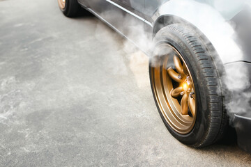 Racing car with golden wheels parked on the cement road and smoke coming from the brake system ,...