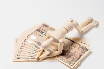 一万円札の上でがっくりするデッサン人形