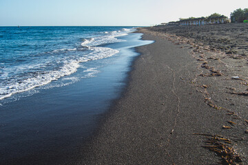 Plage de sable noir et village de Perissa, sur l'ile de Santorin, en Grèce, au mois d'avril 2024. 