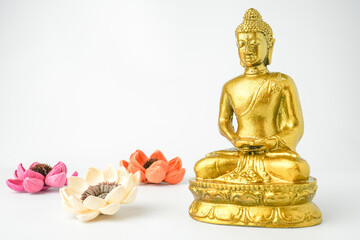 A golden statue of a Buddhist figure meditating decorate with colorful flowers facing the front...