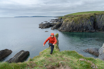 Hiker walks on cliffs, on Wild Atlantic Way coast, Ireland