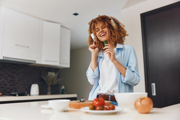 Happy African American woman enjoying healthy lifestyle by eating fresh vegetables in her home...