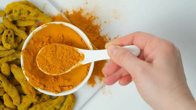 Chef showing turmeric powder shaking it off with spoon, top view, slow motion
