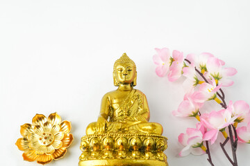 A golden statue of a Buddhist figure meditating decorate with colorful flowers facing the front...