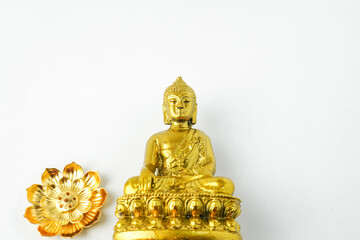 A golden statue of a Buddhist figure meditating decorate with colorful flowers facing the front isolated on white background. Concept for Vesak Day and Enlightenment Day