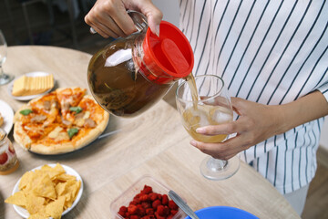 Hand Pouring Ice Lemon Tea Into The Glass for Guest to Drinks on Party at Home
