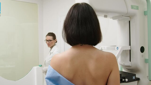 A doctor installs a digital mammograph for a patient. Women's health concept. A woman undergoes a mammogram in a modern clinic under the supervision of a doctor.