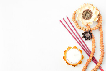 Isolated Empty white background decorated with colorful flowers, red colored incense, round white candle and prayer beads. Concept for Vesak Day and Enlightenment Day. Empty blank copy text space