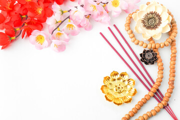 Isolated Empty white background decorated with colorful flowers, red colored incense and prayer beads. Concept for Vesak Day and Enlightenment Day. Empty blank copy text space