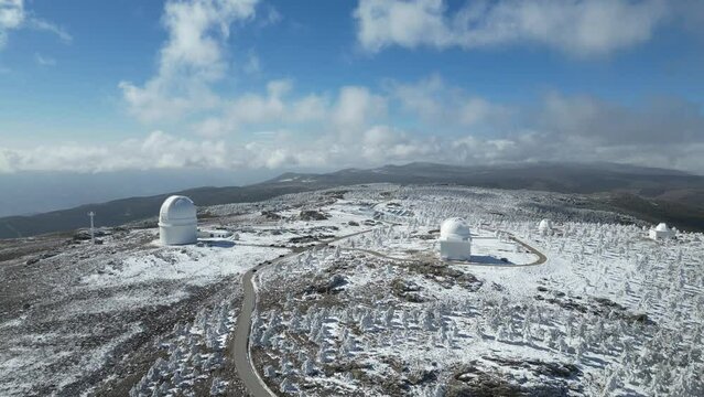 Vista a&eacute;rea de monta&ntilde;as nevadas y c&uacute;pulas de observatorio del calar alto.