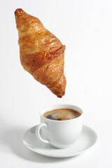 Croissant hanging over coffee