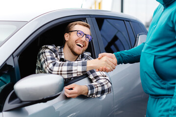 Man buying car and shaking hands with salesman against blurred auto, closeup. Concept of choosing...
