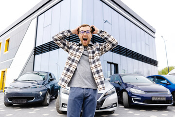 A young man is very impressive and happy, standing in front of his new car