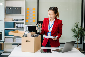 Happy and excited young beautiful Asian woman office worker celebrating her resignation, carrying her personal stuff.