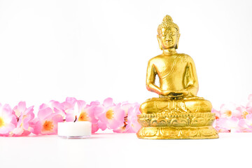 A golden statue of a Buddhist figure meditating decorate with colorful flowers and round white...