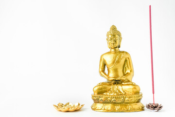 A golden statue of a Buddhist figure meditating decorate with colorful flowers and red colored incense isolated on white background. Concept for Vesak Day and Enlightenment Day