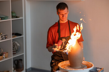 A potter burns a jug with a gas burner on a potter's wheel. 