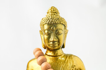 A golden statue of a Buddhist figure meditating and wearing prayer beads facing the front isolated on white background. Concept for Vesak Day and Enlightenment Day