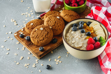 tasty nutritious oatmeal with fruits and berries on a light stone background
