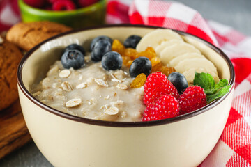 tasty nutritious oatmeal with fruits and berries on a light stone background