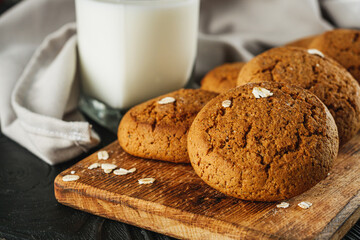 oatmeal cookies with a glass of milk on a black wooden rustic background